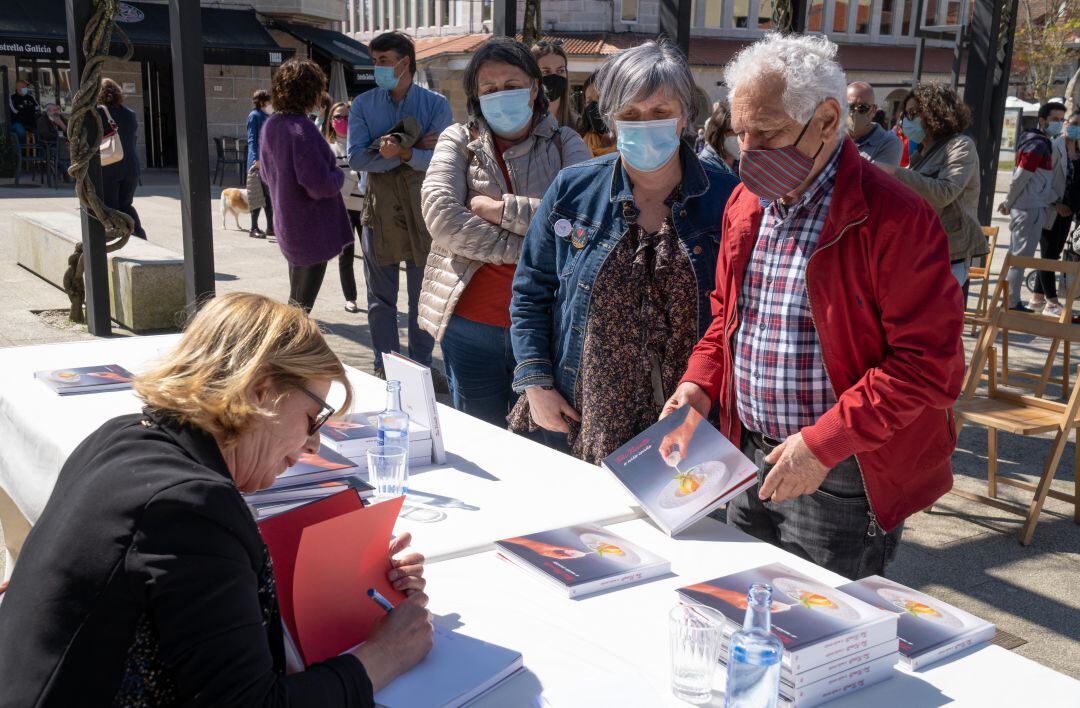 La chef Toñi Vicente firmando su libro a varios vecinos de Tomiño en la plaza do Seixo.