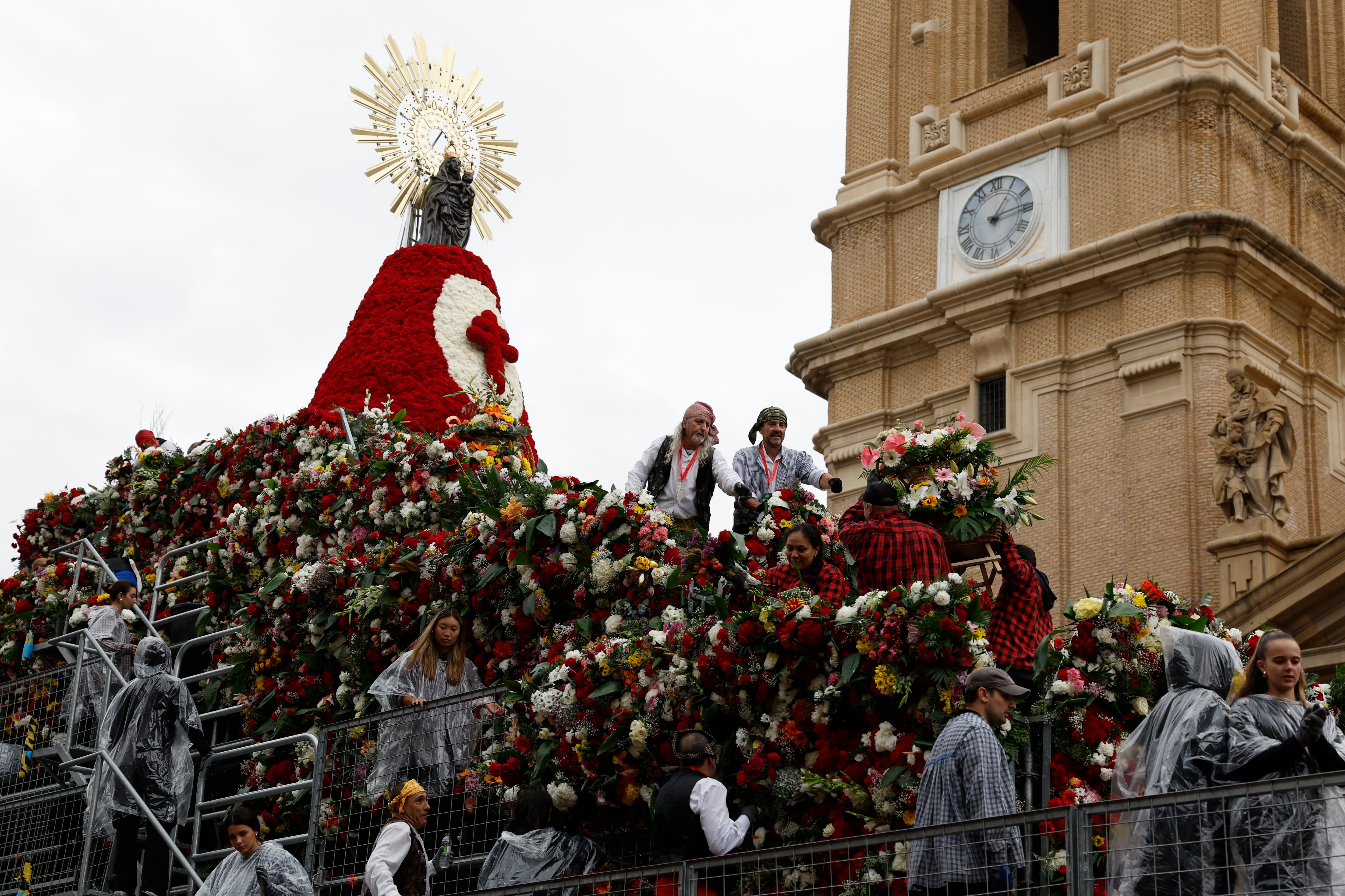 ZARAGOZA, 12/10/2024.- Varias personas colocan las flores a los pies de la Virgen del Pilar durante la tradicional Ofrenda de Flores a la Virgen este sábado en Zaragoza. EFE/ Javier Cebollada
