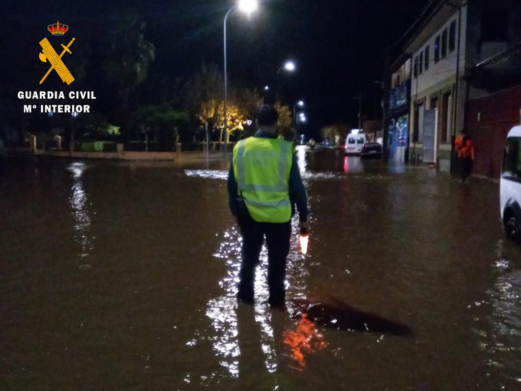 Un agente de la Guardia Civil desvía el tráfico en una carretera anegada en Zarza de Granadilla