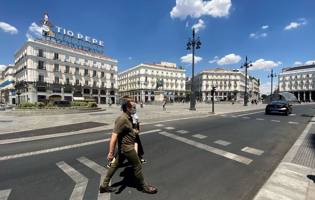 Dos personas cruzan la calle en la Puerta del Sol de Madrid