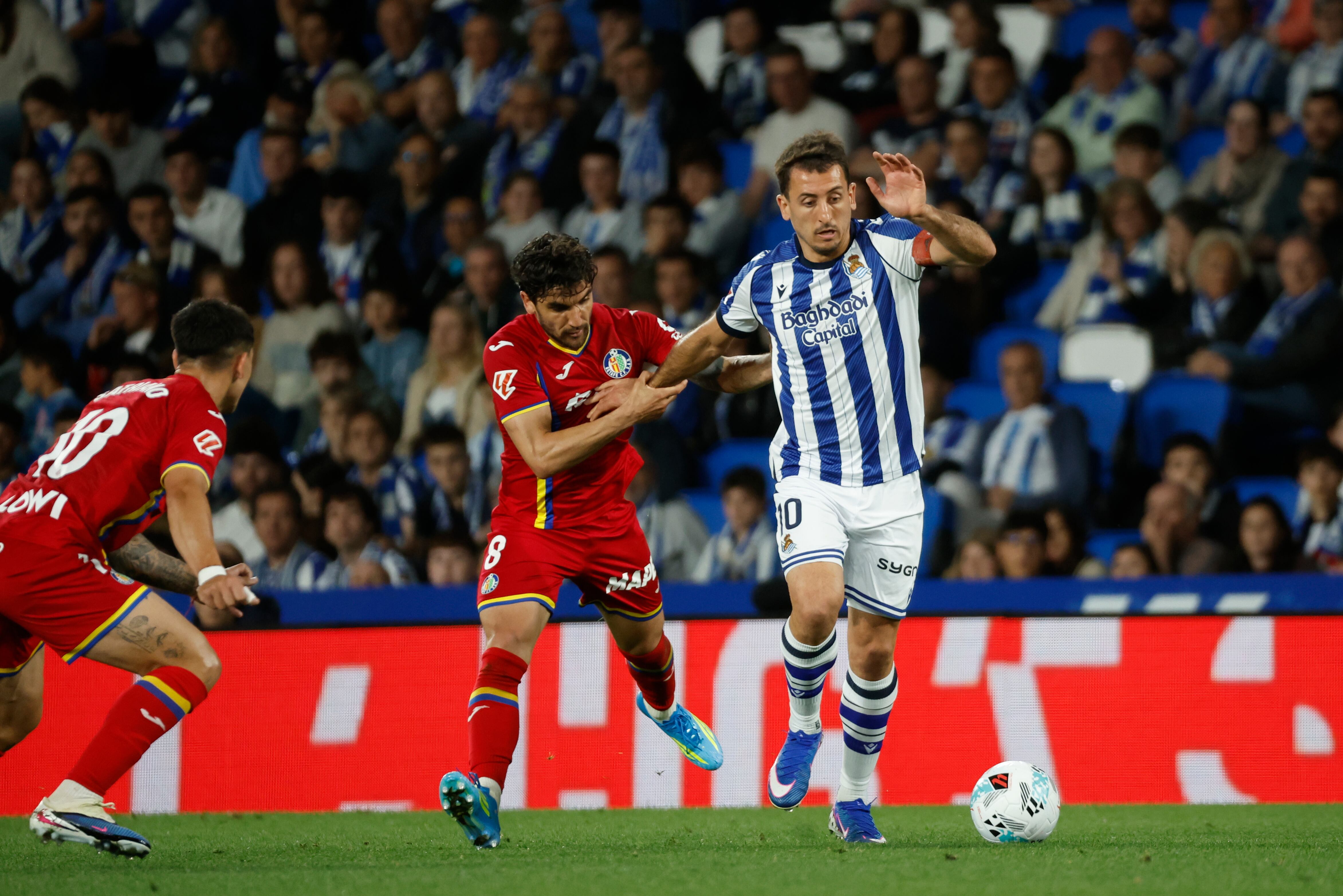 SAN SEBASTIÁN, 22/04/2026.- El centrocampista uruguayo del Getafe Mauro Arambarri (c) pelea un balón con el delantero de la Real Sociedad Mikel Oyarzabal (d) durante el partido de la jornada 33 de LaLiga entre la Real Sociedad y Getafe CF, este miércoles en el estadio de Anoeta en San Sebastián. EFE/Juan Herrero