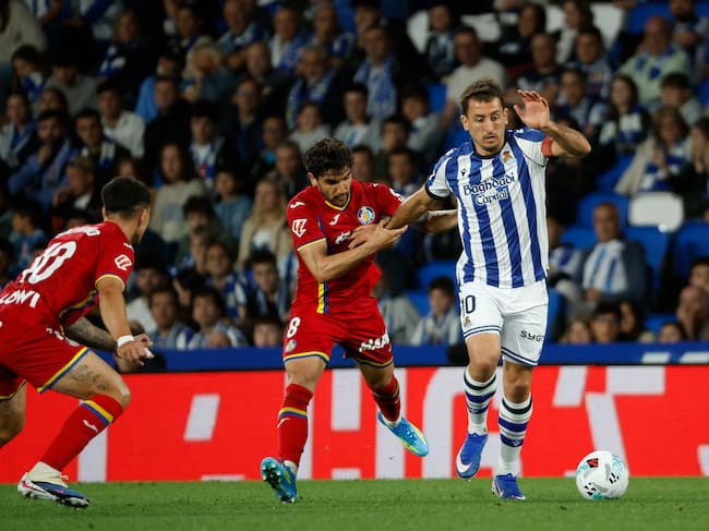 SAN SEBASTIÁN, 22/04/2026.- El centrocampista uruguayo del Getafe Mauro Arambarri (c) pelea un balón con el delantero de la Real Sociedad Mikel Oyarzabal (d) durante el partido de la jornada 33 de LaLiga entre la Real Sociedad y Getafe CF, este miércoles en el estadio de Anoeta en San Sebastián. EFE/Juan Herrero
