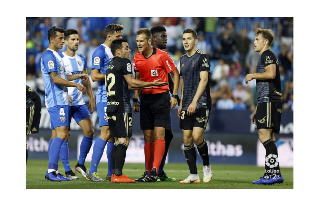 Jugadores del Oviedo y el Málaga protestan una decisión del colegiado.