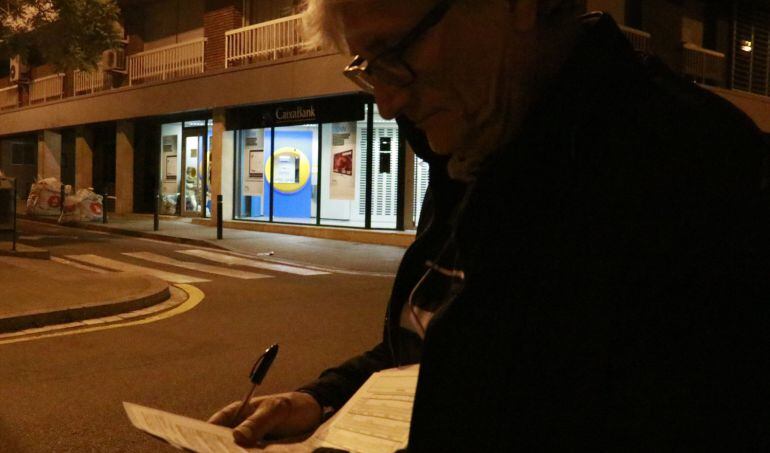 Un voluntari del recompte de persones sensellar; al fons, un home dorm dins un caixer