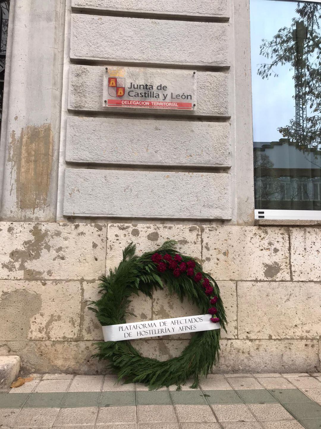 La Plataforma de Afectados de la Hostelería de Palencia ha dejado una corona de flores a las puertas de la Delegación Territorial de la Junta simbolizando el momento que atraviesa el sector