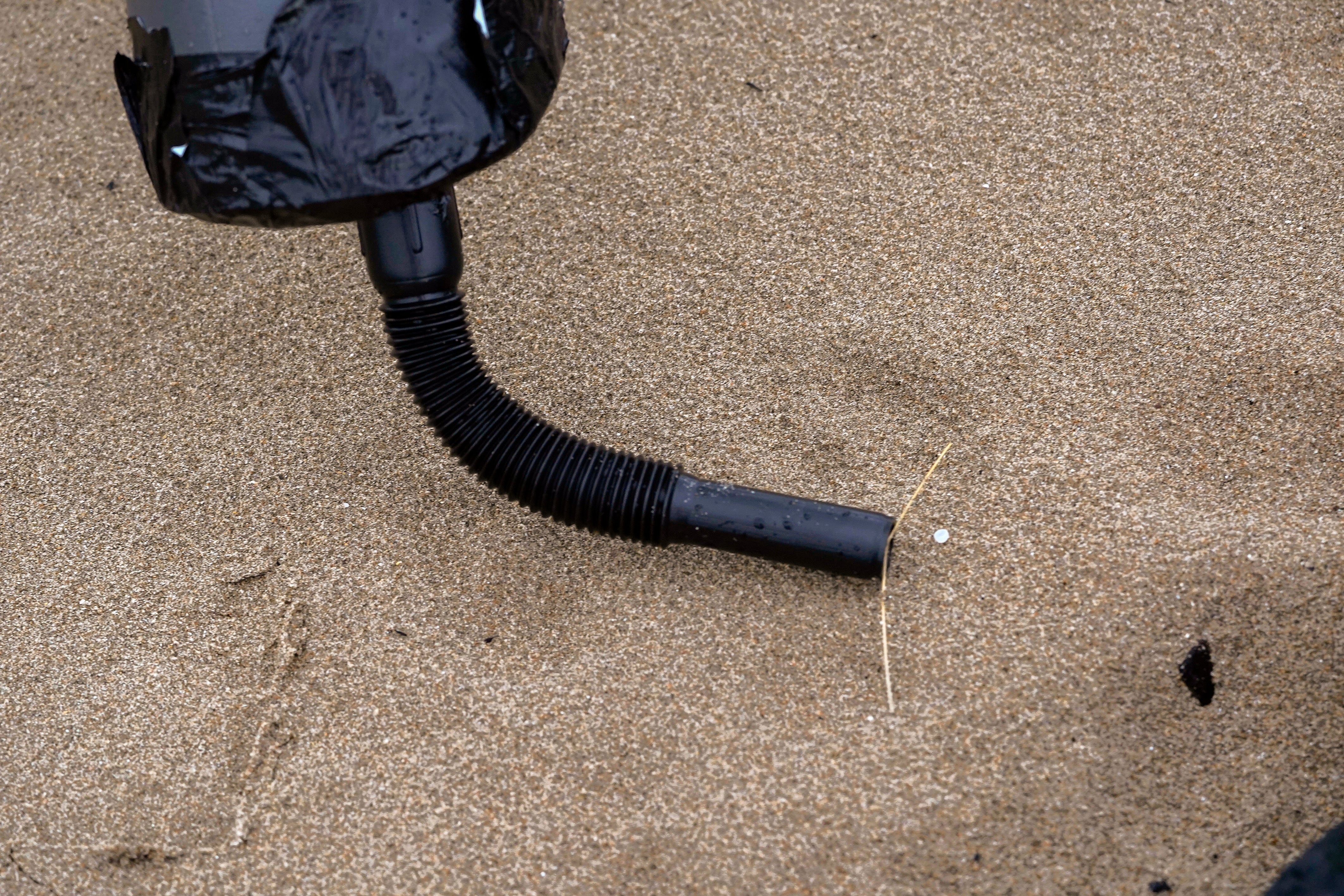 PLAYA DE VEGA (ASTURIAS), 11/01/2024.- Un operario recoge pellets de plástico con un tubo más fino en el aspirador enla limpieza este jueves de la playa de Vega (Asturias), cuya costa continúa recibiendo con cada marea pellets de plástico procedentes de los contenedores perdidos por el buque Toconao en aguas portuguesas, aunque en cantidades &quot;muy limitadas&quot; que son de &quot;cientos de gramos&quot; en algunas playas. EFE/Paco Paredes
