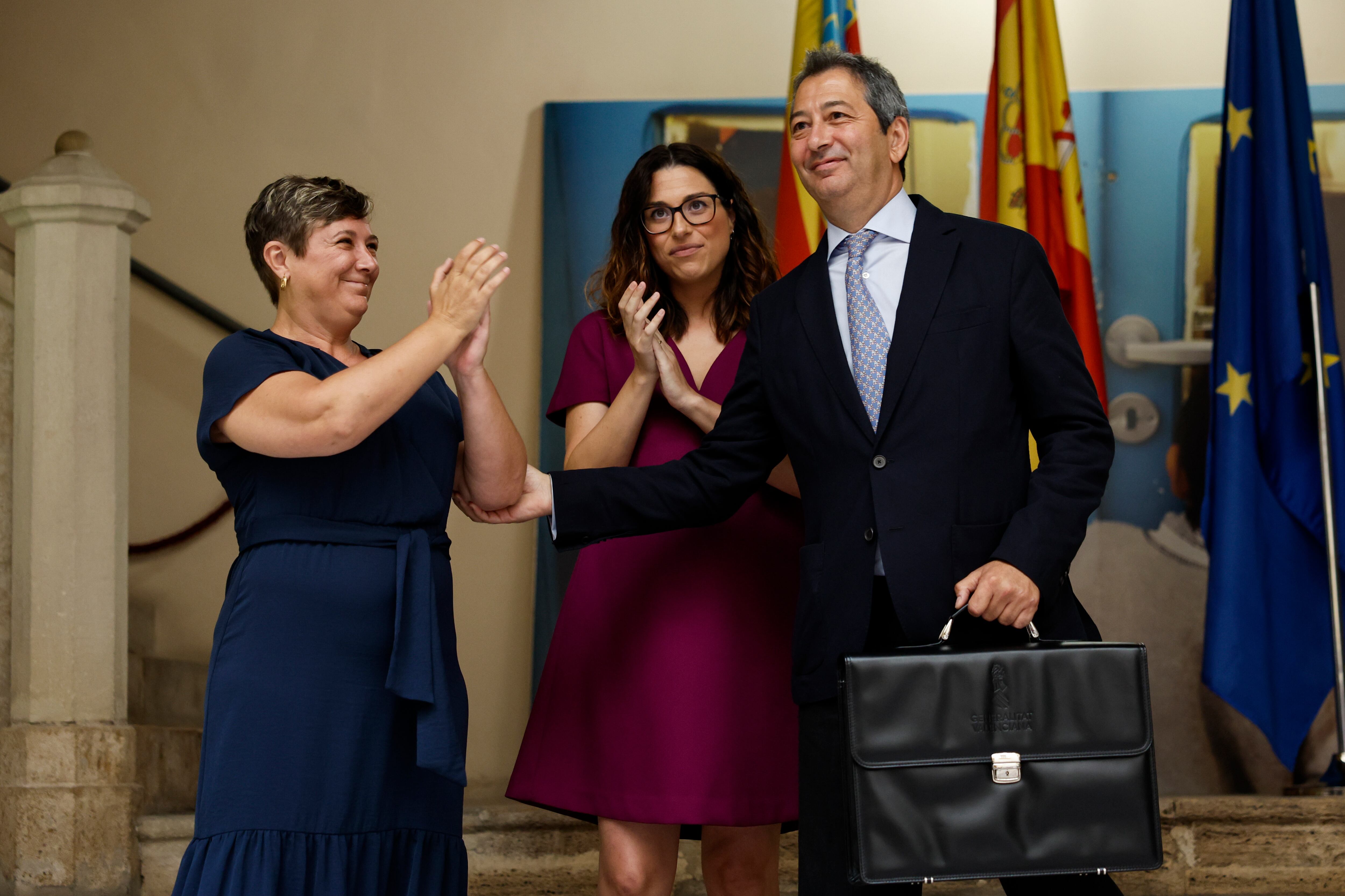 El vicepresidente primero y conseller de Cultura y Deporte, Vicente Barrera Simó (d), recibe las carteras de sus antecesoras, la vicepresidenta en funciones, Aitana Mas, y la consellera de Educación, Cultura y Deporte en funciones, Raquel Tamarit (i), durante la jornada previa a la primera reunión del nuevo ejecutivo de la Generalitat.