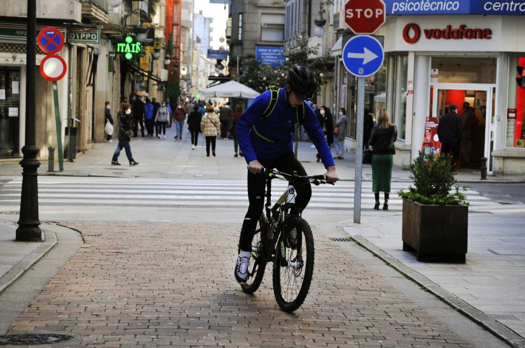 Una persona circula en bicicleta por una vía del centro el mismo día en que se levanta el cierre perimetral del municipio y se reabre la hostelería, en O Carballiño, Ourense.