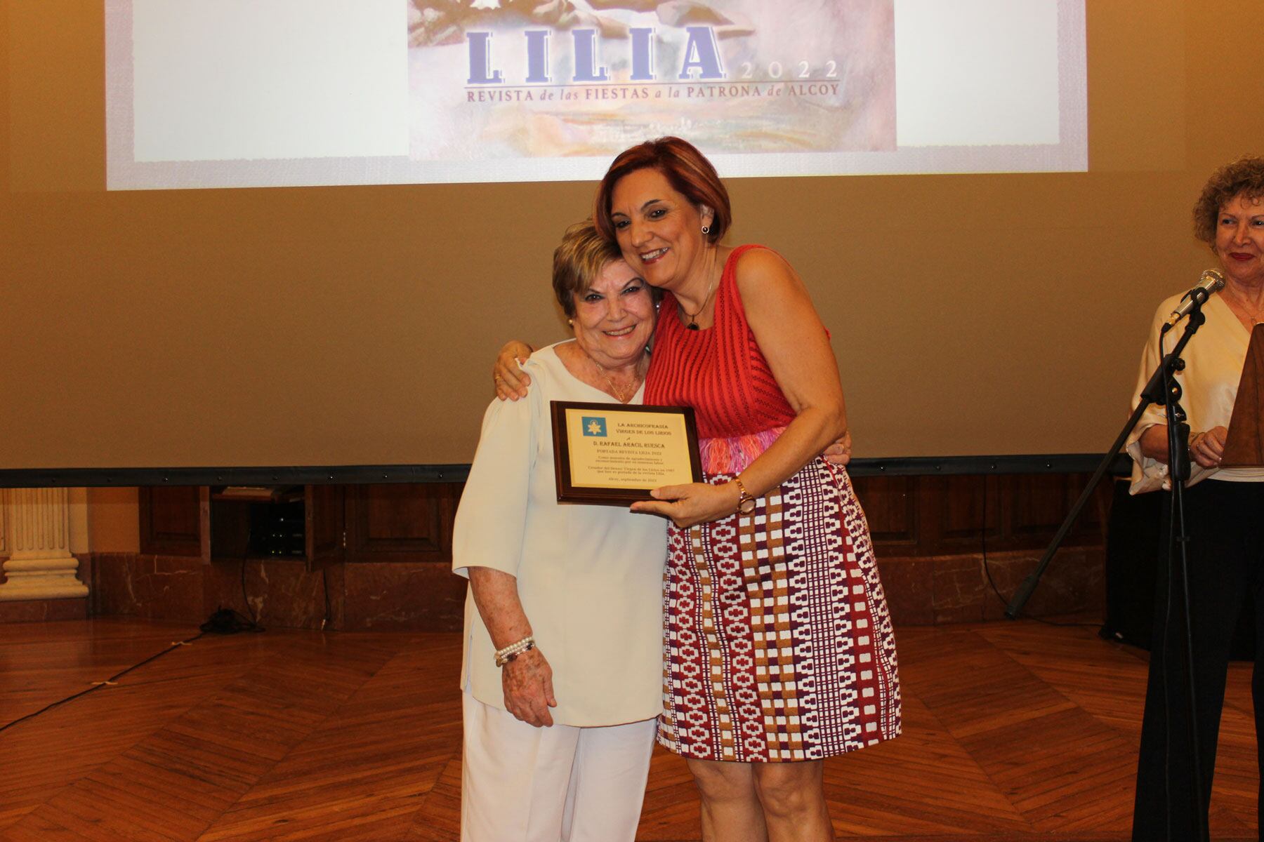 Reme Perelló le entrega un pequeño obsequio a Alicia Tortosa, esposa de Rafael Aracil Ruesca