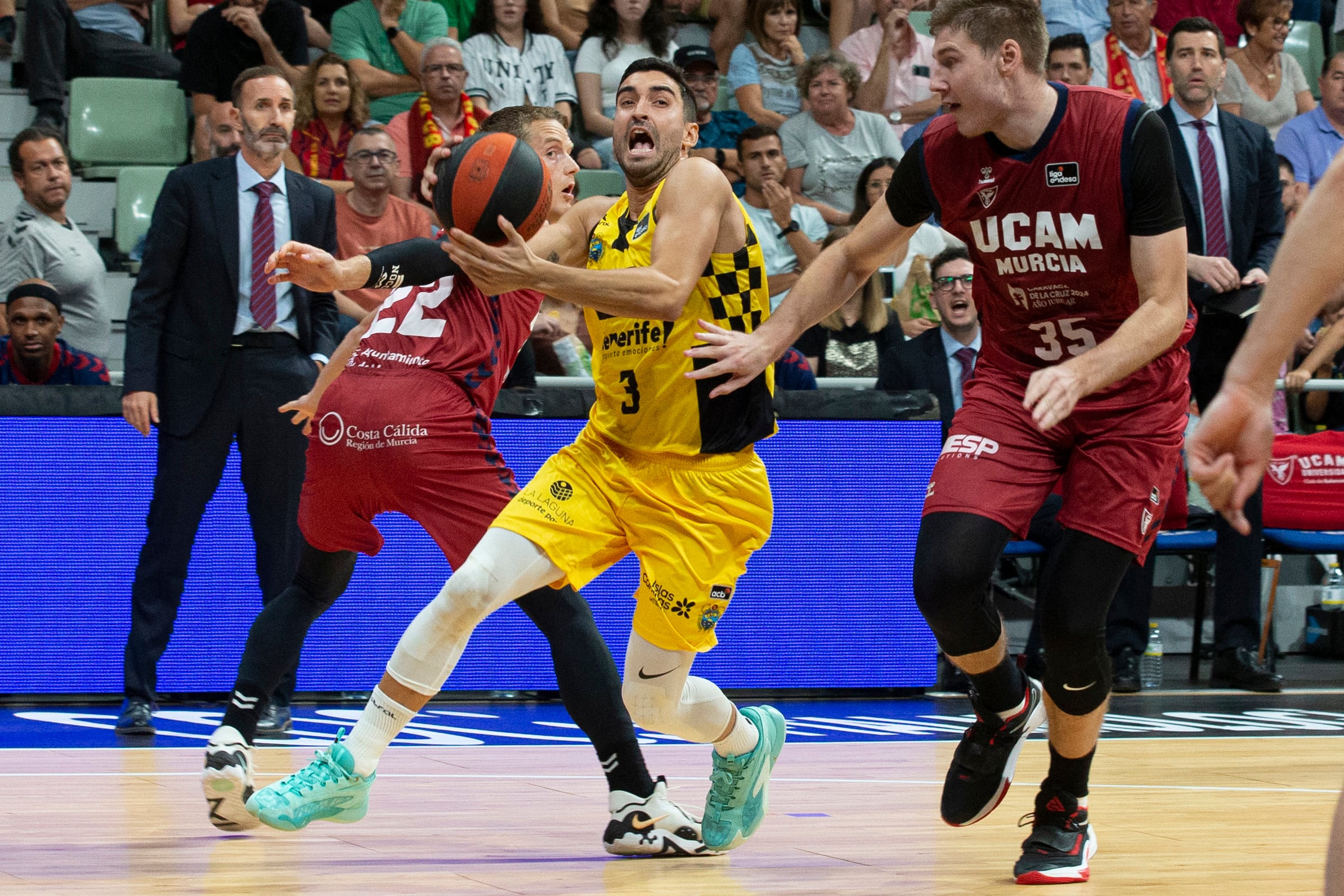 MURCIA, 30/09/2023.- El escolta de Lenovo Tenerife Jaime Fernández (c) controla el balón ante la oposición del pívot sueco de UCAM Murcia Simon Birgander (d), durante el partido de la tercera jornada de la Liga Endesa, que están disputando este sábado en el Palacio de los Deportes de Murcia. EFE/Marcial Guillén