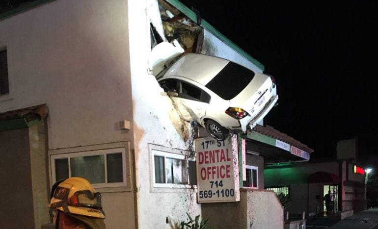 Fotografía facilitada por los bomberos del condado de Orange que muestra un coche empotrado contra la segunda planta de un local de oficinas en Santa Ana, California.