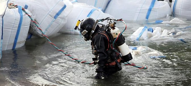 Un submarinista especializado de una empresa de salvamento coloca una barrera de sacos de arena en el río Rin cerca de Coblenza