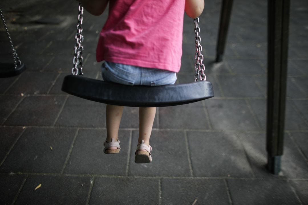 Un niña subida a un columpio.