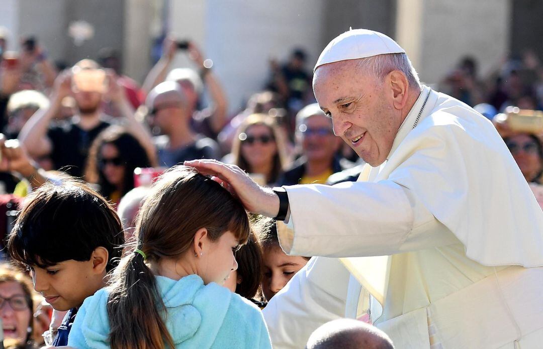 El papa Francisco (d) bendice a una niña durante su tradicional audiencia semanal en la Plaza de San Pedro del Vaticano.