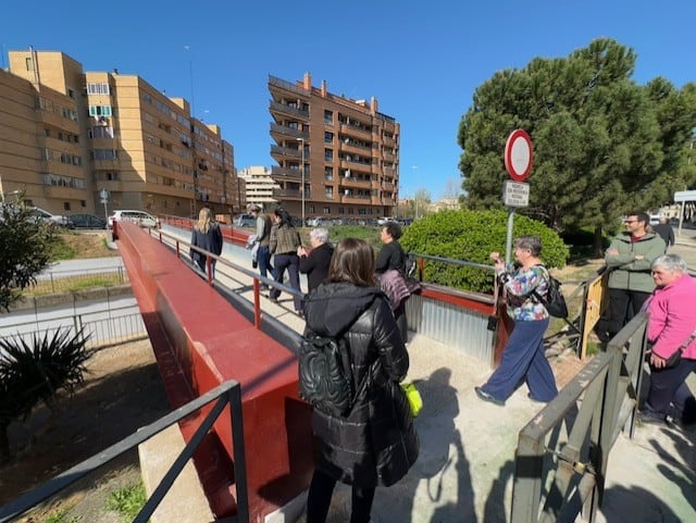 Vecinos paseando en el día de reapertura de la pasarela sobre el río Isuela