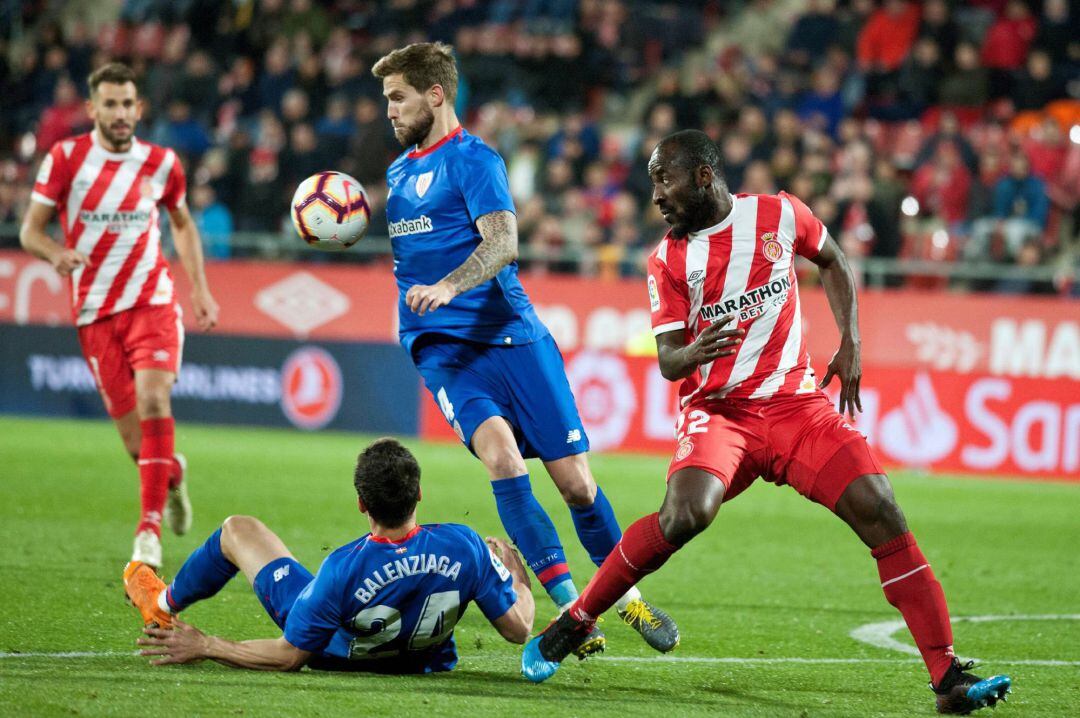 El defensa del Athletic de Bilbao Íñigo Martínez (c, arriba) controla un balón ante Seydou Doumbia, del Girona, durante el partido de Liga en Primera División disputado este viernes en el Estadio Municipal Montilivi