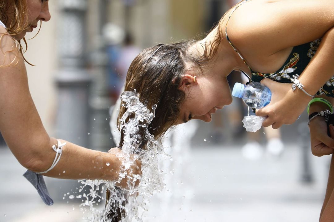 Una mujer se refresca en una fuente antes las intensas temperaturas que se registran debido a la llegada de la ola de calor