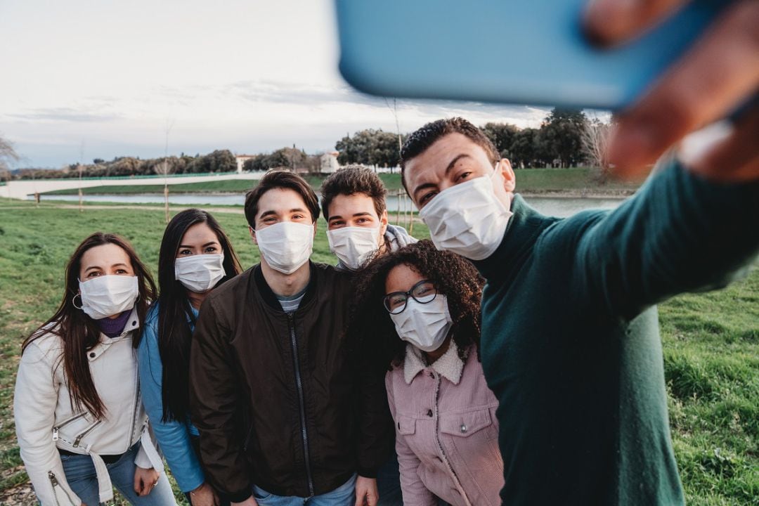 Grupo de jóvenes con mascarilla se hace un selfie