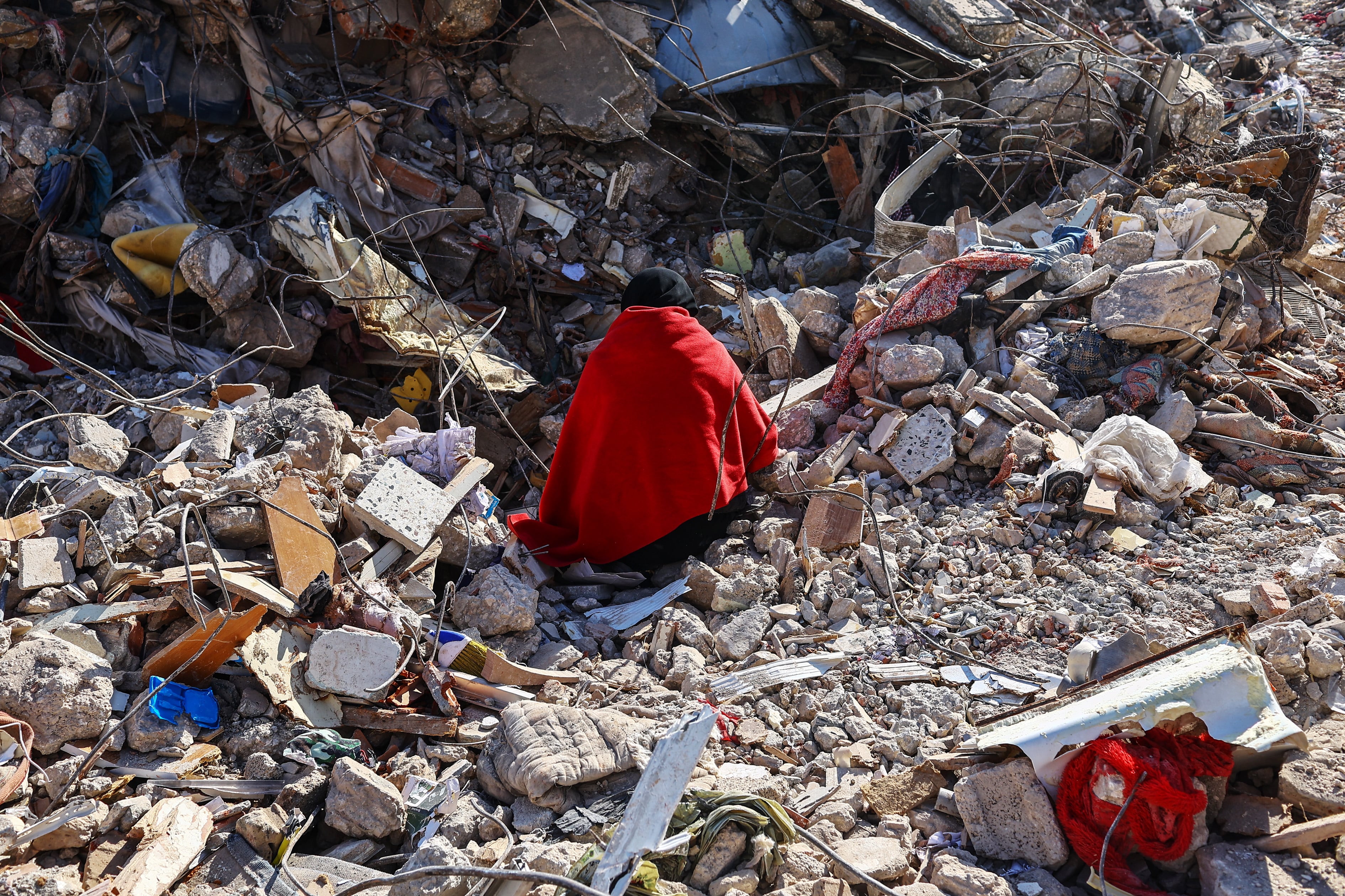 Una mujer sentada sobre los escombros de su casa espera los cuerpos de sus familiares en el lugar de los edificios derrumbados tras un fuerte terremoto, en Hatay, Turquía.