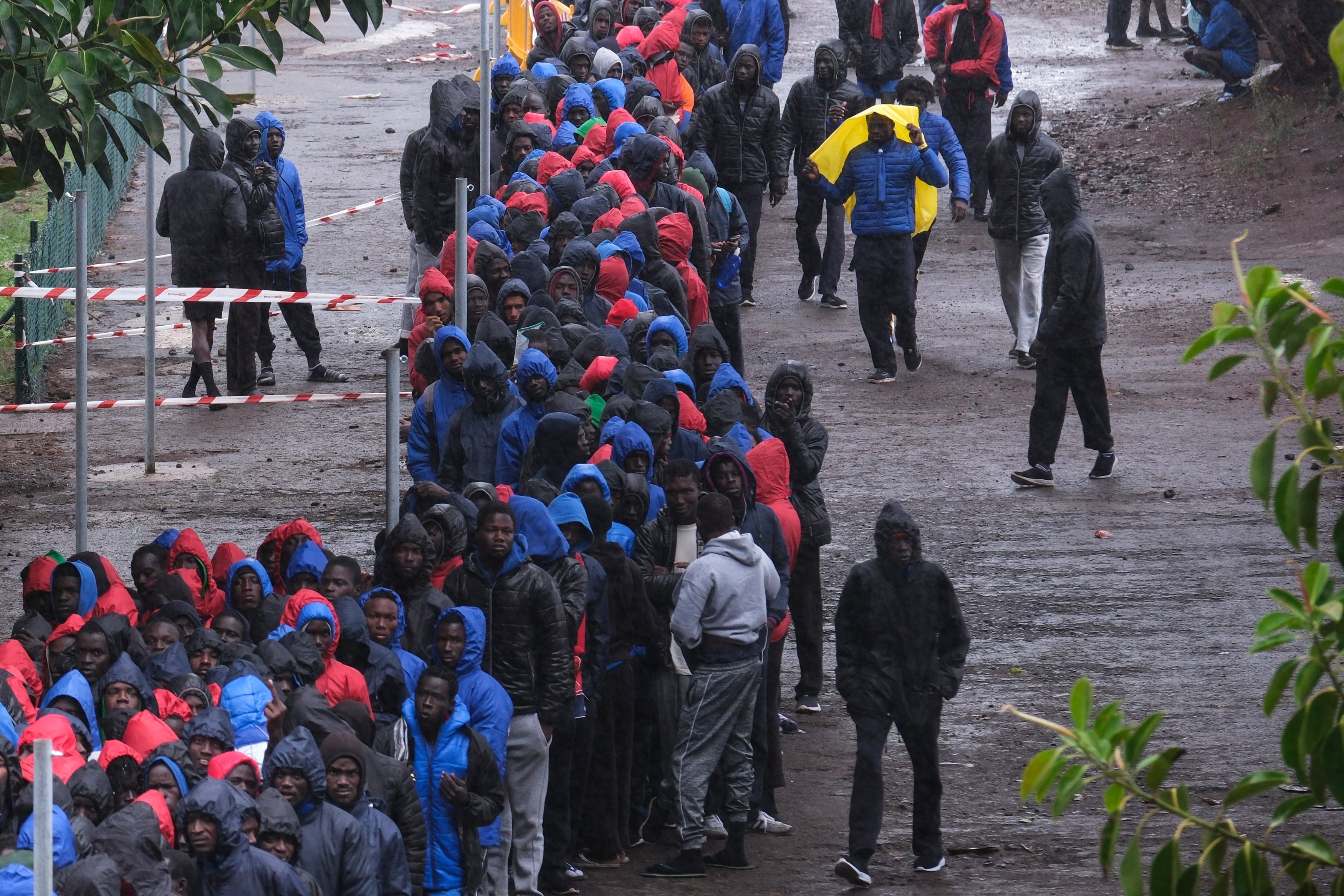 Cientos de migrantes de origen subsahariano, en su mayoría senegaleses, hacen fila bajo la lluvia este domingo para acceder al centro de acogida para migrantes de Las Raíces en Tenerife.