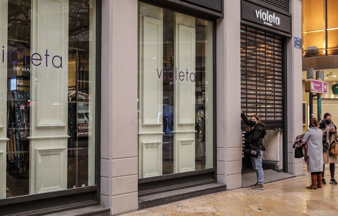 Una trabajadora del comercio Violeta cierra el establecimiento el primer día del cierre total de la hostelería y de tiendas a las 18.00h en València. 