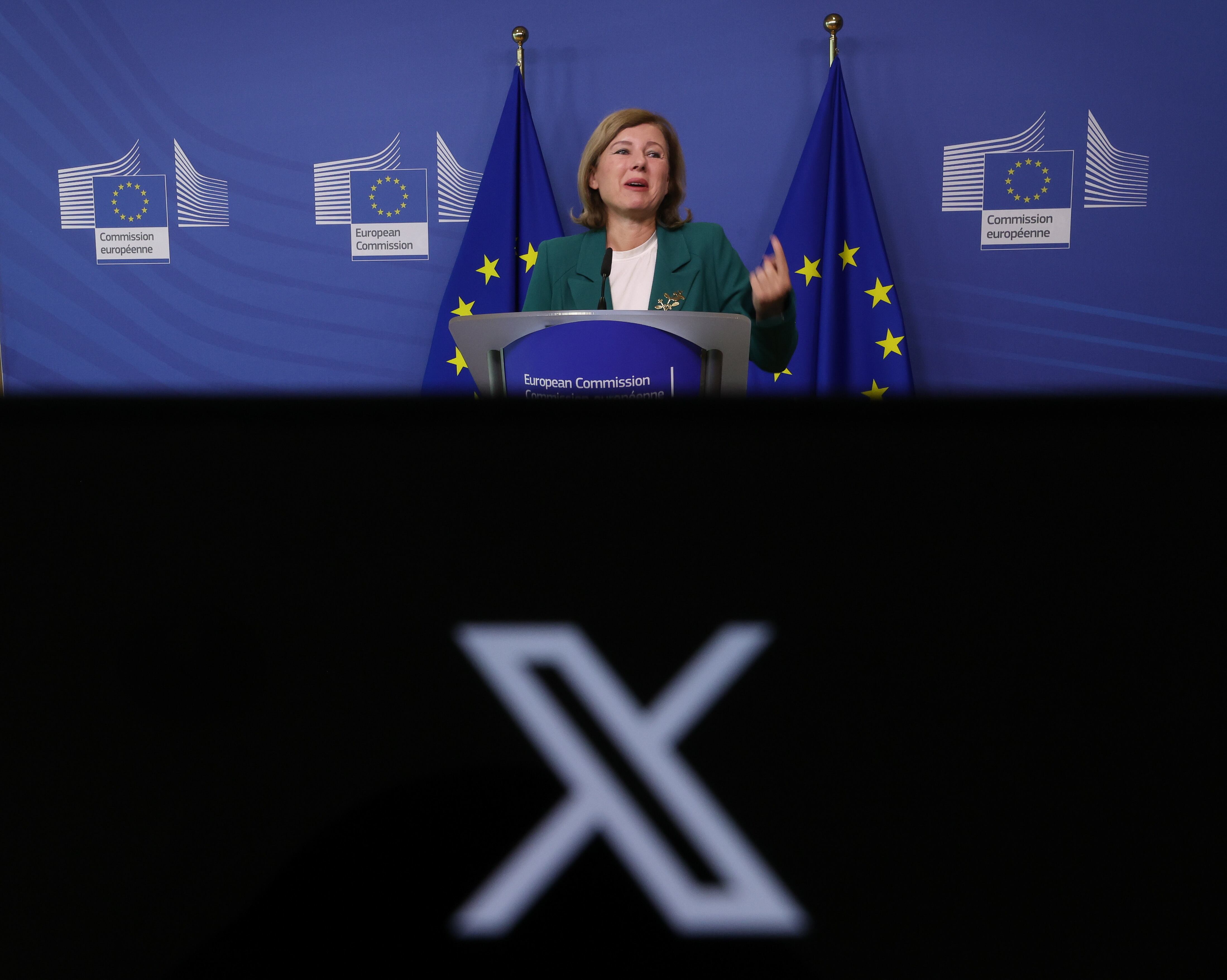 El logo de X, anteriormente conocida como Twitter, con el fondo de la vicepresidenta de la Comisión Europea para valores y transparencia, Vera Jourova, durante la rueda de prensa en la que ha entregado los datos de la red social que mas desinforma