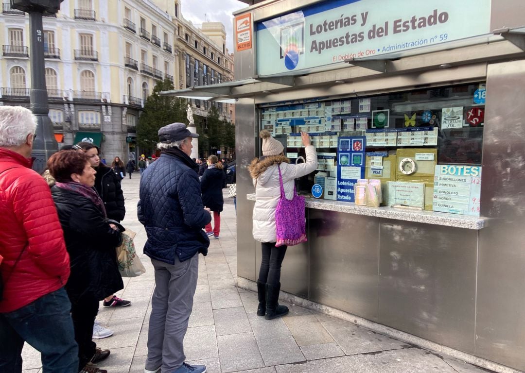 Una mujer compra un décimo de Lotería de Navidad en una Administración en la plaza de Puerta del Sol