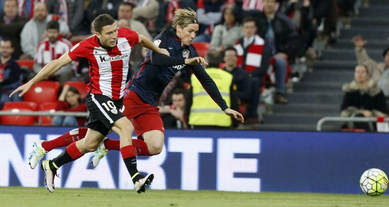 El delantero del Atlético de Madrid Fernando Torres (d) cae ante De Marcos, del Athletic de Bilbao, durante el partido de Liga en Primera División disputado esta noche noche en el estadio de San Mamés, en Bilbao