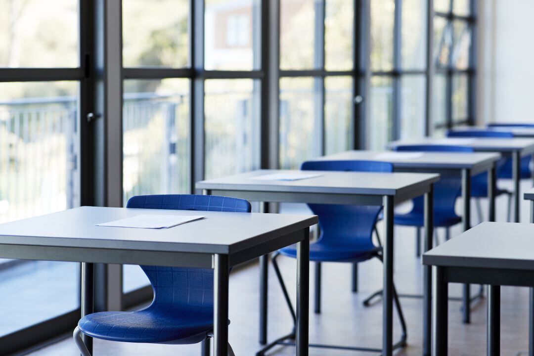 Un aula con mesas y sillas esperando a los alumnos.