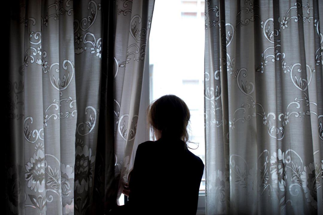 Una mujer observa a través de la ventana de su vivienda, en la que permanece confinada desde que el Gobierno decretase el estado de alarma por la crisis del coronavirus