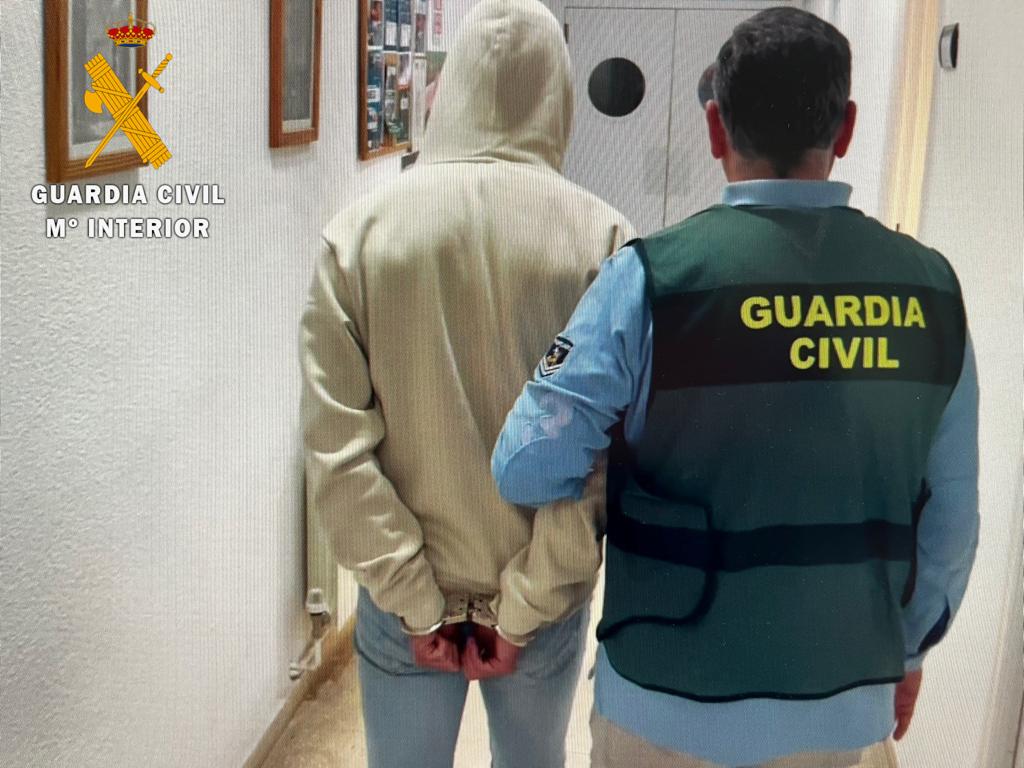 Un agente de la Guardia Civil acompaña a uno de los detenidos