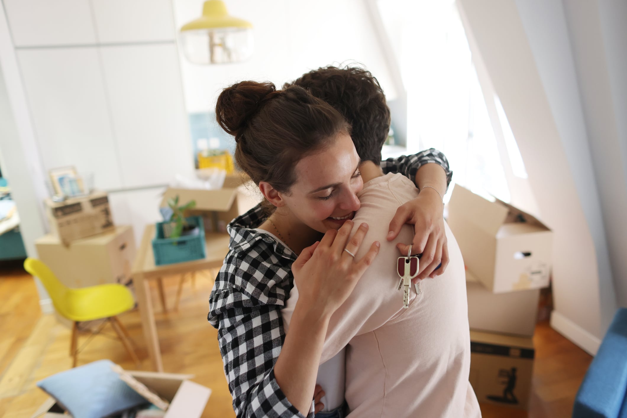 Una pareja joven abrazándose tras mudarse a su nuevo hogar.