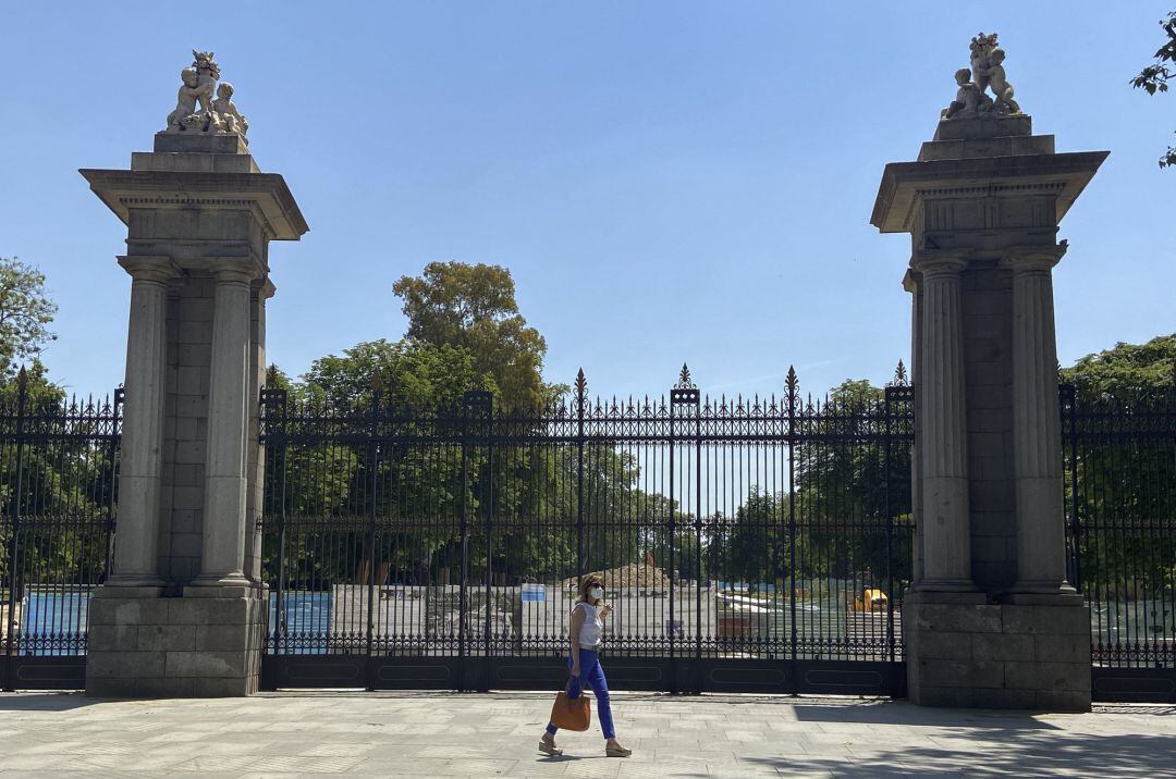 Una mujer pasa al lado de una de las puertas del parque de El Retiro.