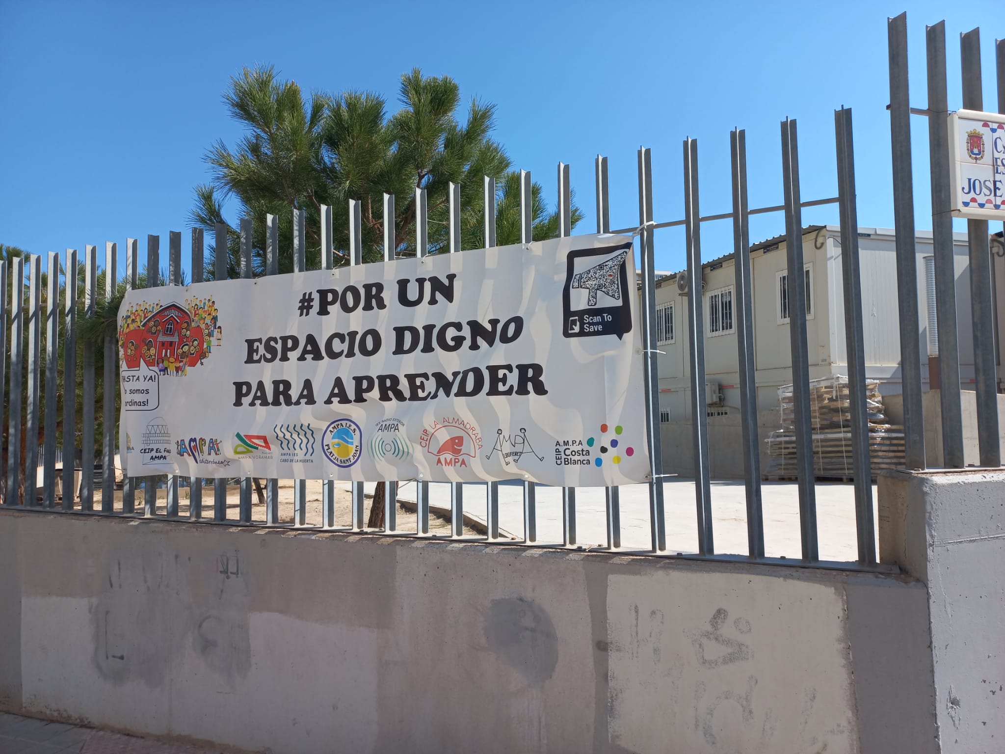 Cartel reivindicativo en el centro del IES Radio Exterior de Alicante que alberga el CEIP La Almadraba con barracones en el patio