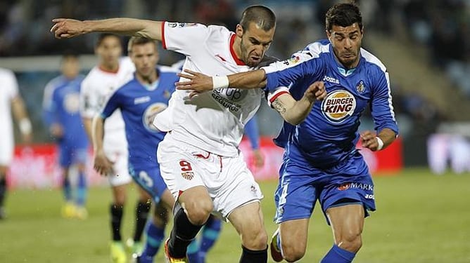 El futbolista del Sevilla Álvaro Negredo y el jugador del Getafe Miguel Torres, durante la disputa del partido correspondiente a la Liga 2011-2012.