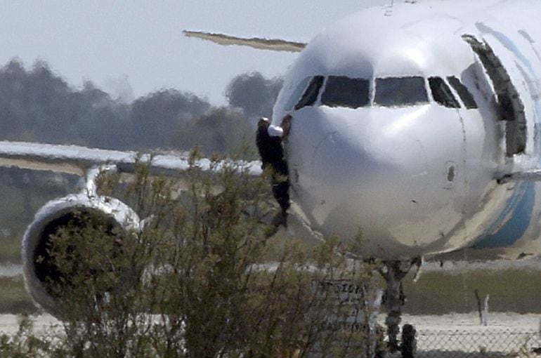 Un hombre se descuelga desde la ventanilla de la cabina del Airbus A320 de Egyptair obligado a aterrizar en el aeropuerto de Lárnaca.