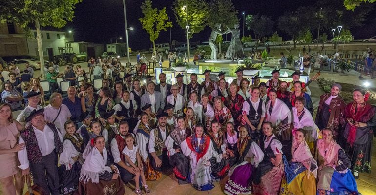 Grupo de personas vestidas con el traje típico de los Noguerones junto al monumento del parque.