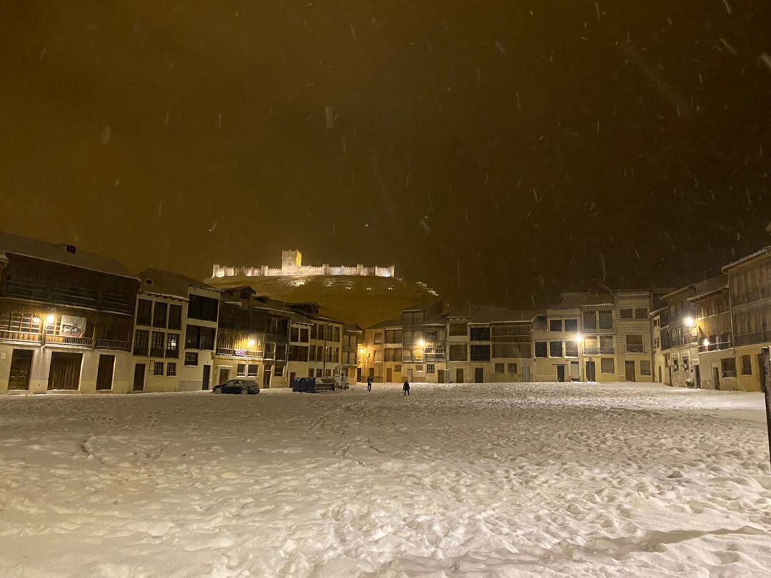 El Castillo de Peñafiel visto desde un Plaza del Coso cubierta por la nieve en la noche de este sábado.