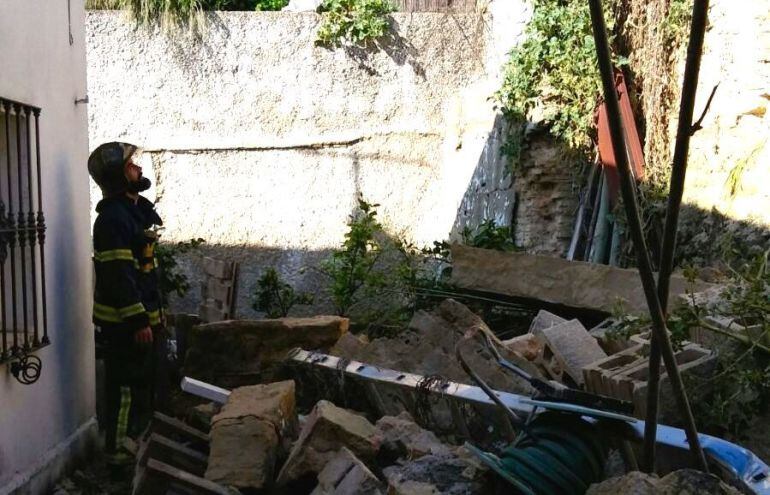 Un bombero observa parte del muro derrumbado en Los Albarizones