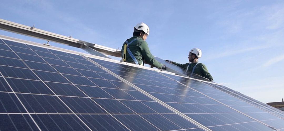 Dos operarios colocan placas solares en un tejado.