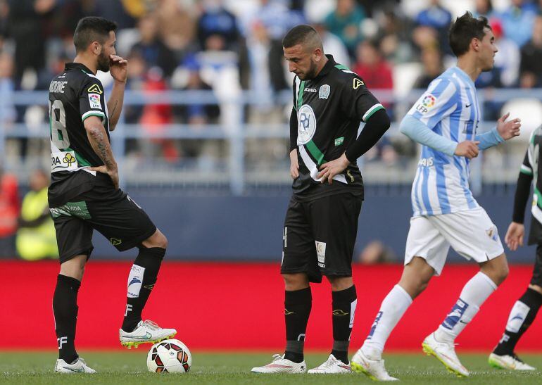 GRA260. MÁLAGA, 15/03/2015.- El centrocampista del Córdoba, Borja García (i) frente a su compañero, el delantero argelino Nabil Ghilas, esperan sacar el balón del centro del área tras encajar el segundo gol del Málaga, durante el partido de la jornada 27ª