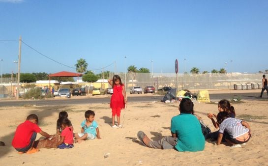 Niños sirios juegan al atardecer en la puerta del Centro de Estancia Temporal de Inmigrantes de Melilla que, con 1.700 internos, está al triple de su capacidad