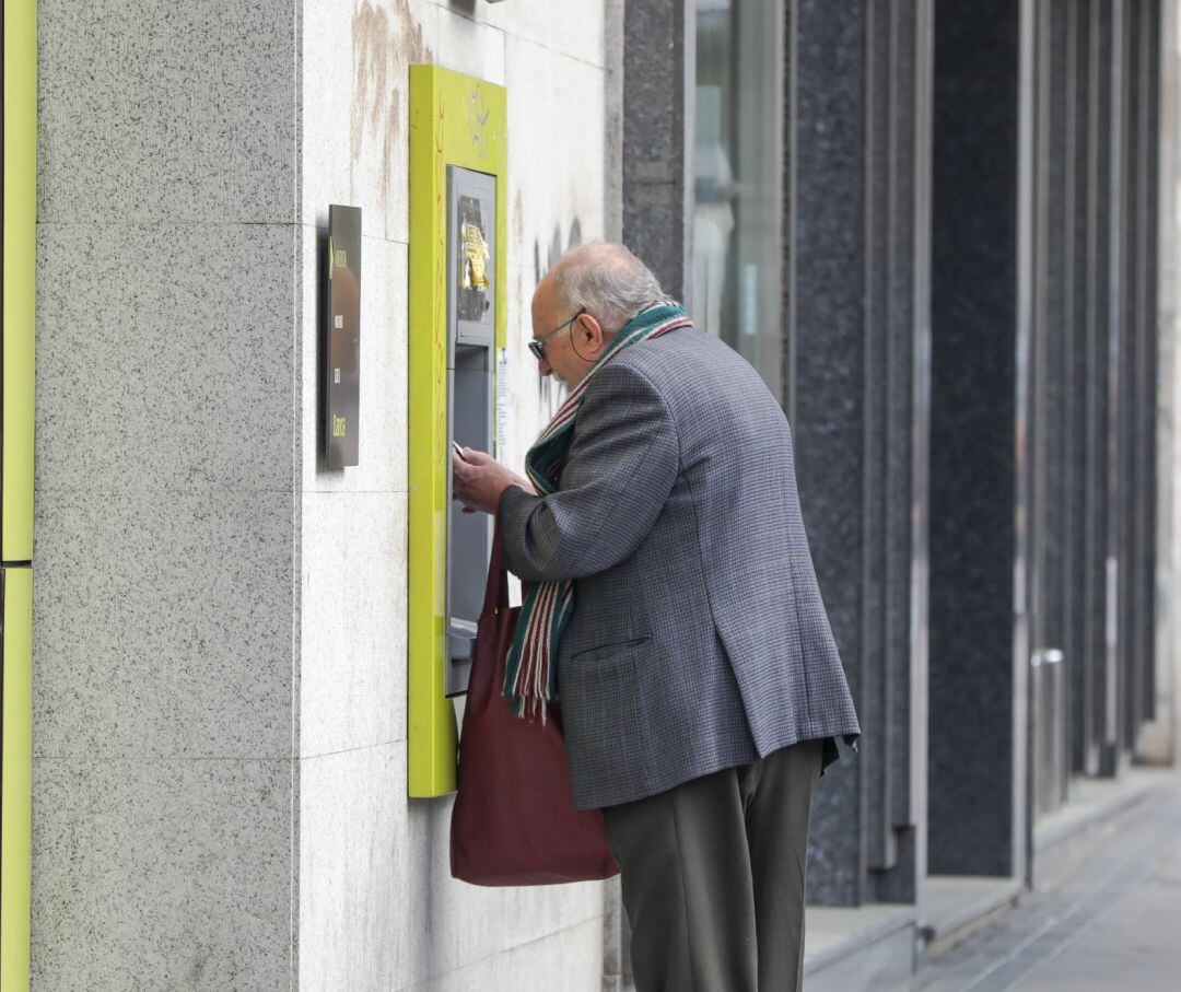 Un anciano saca dinero de un cajero de la capital tras el anuncio del estado de alarma