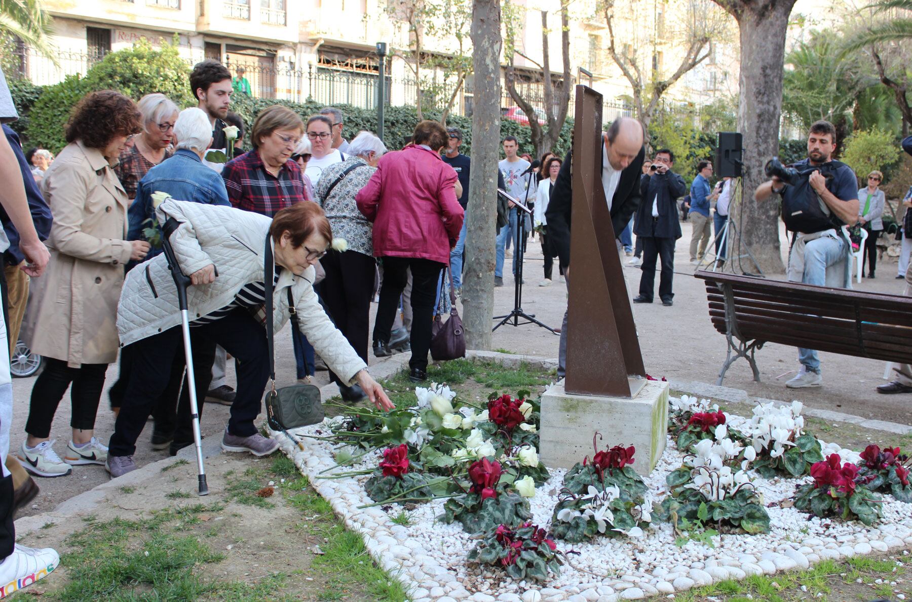 Una familiar de una de las personas fallecidas en DomusVi Alcoy deja una rosa blanca en el monumento a los que lucharon contra la COVID del parque de La Glorieta