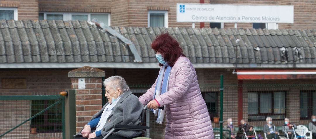 Una mujer pasea a una anciana en silla de ruedas, en las inmediaciones de una residencia 