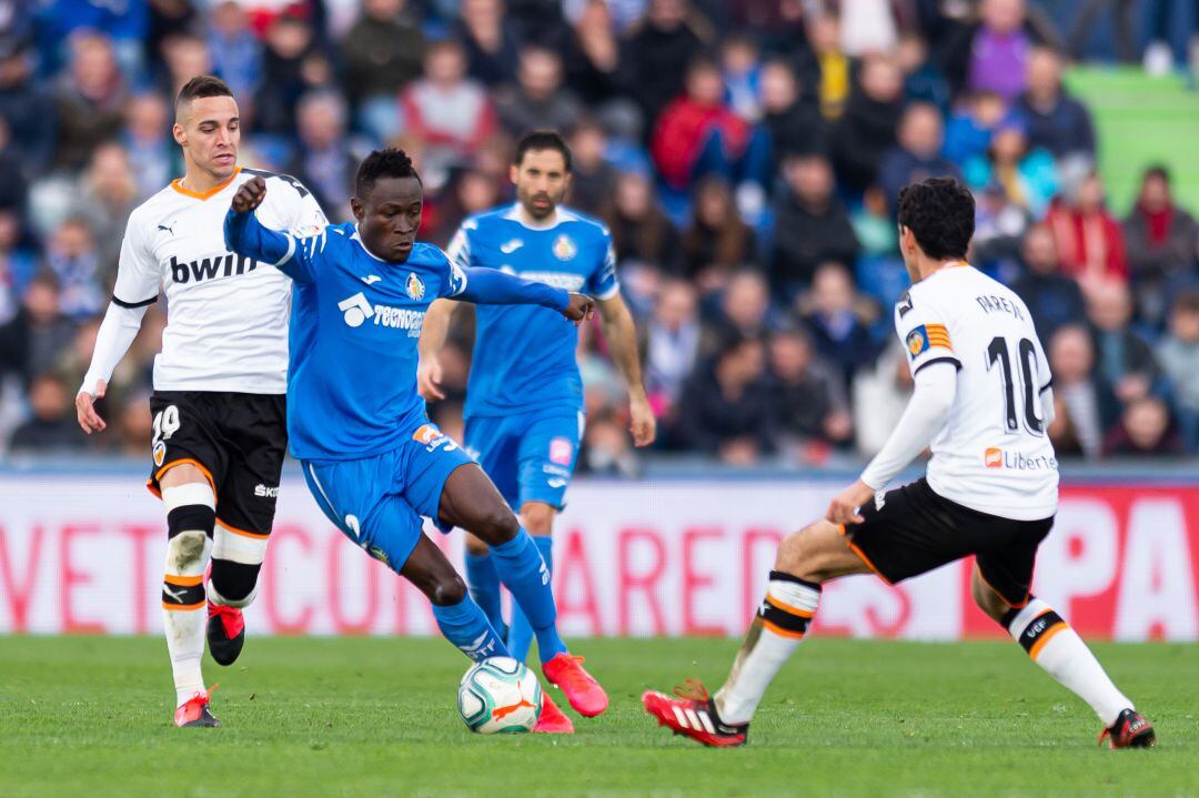 El jugador del Getafe CF Djené intenta sortear a Dani Parejo tras deshacerse de Rodrigo Moreno, (ambos del Valencia CF) en el partido del pasado sábado en el Coliseum