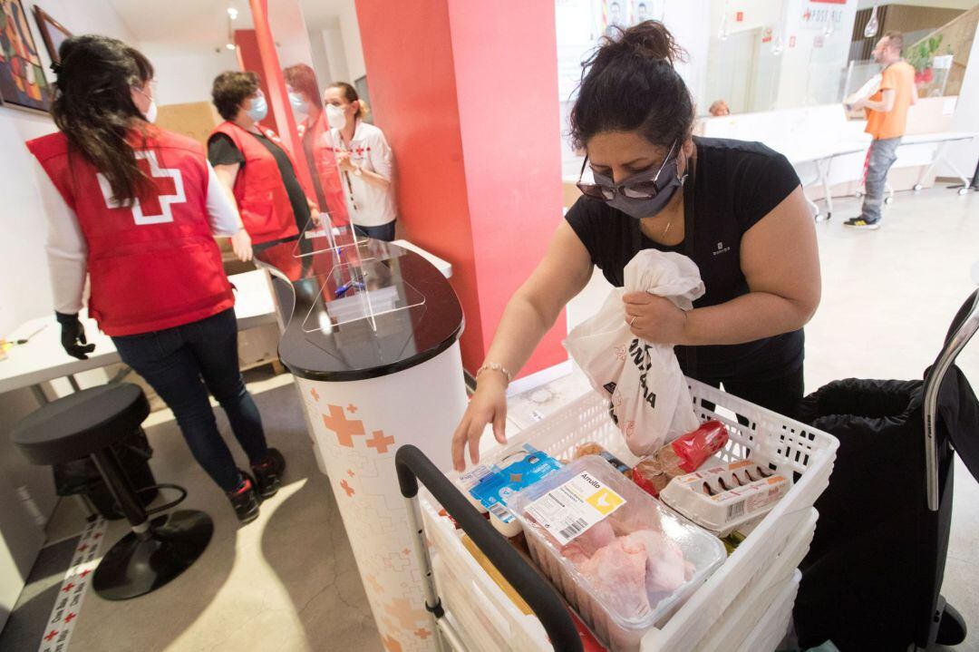 Una ciudadana recoge su lote de alimentación básica en el almacén de la Cruz Roja en Barcelona