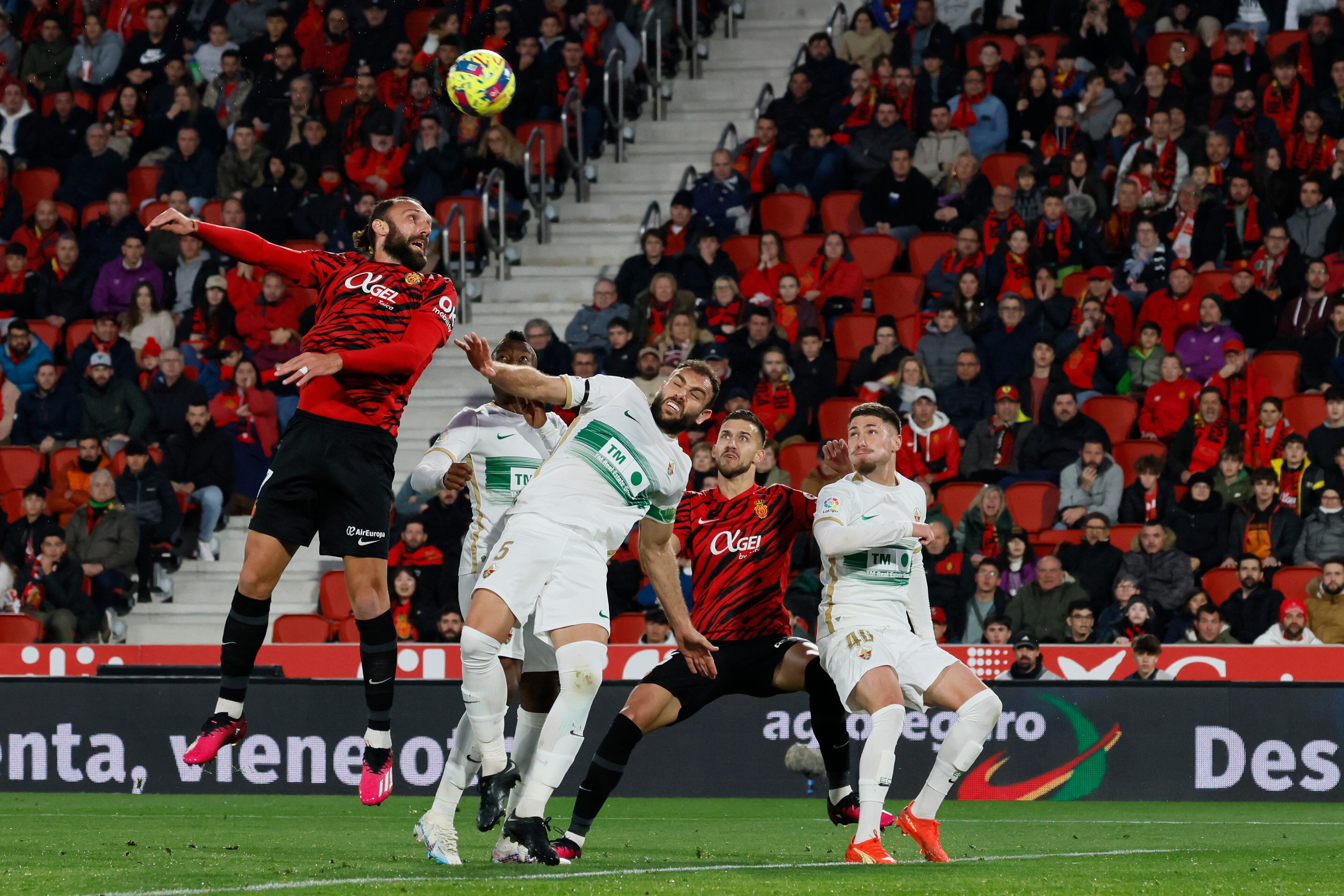 PALMA DE MALLORCA, 04/03/2023.- El delantero del Mallorca Vedat Muriqi (i) salta a por un balón ante Gonzalo Verdú (c), del Elche, durante el partido de Liga en Primera División que RCD Mallorca y Elche CF disputan este sábado en el estadio de Son Moix, en Palma de Mallorca. EFE/Cati Cladera