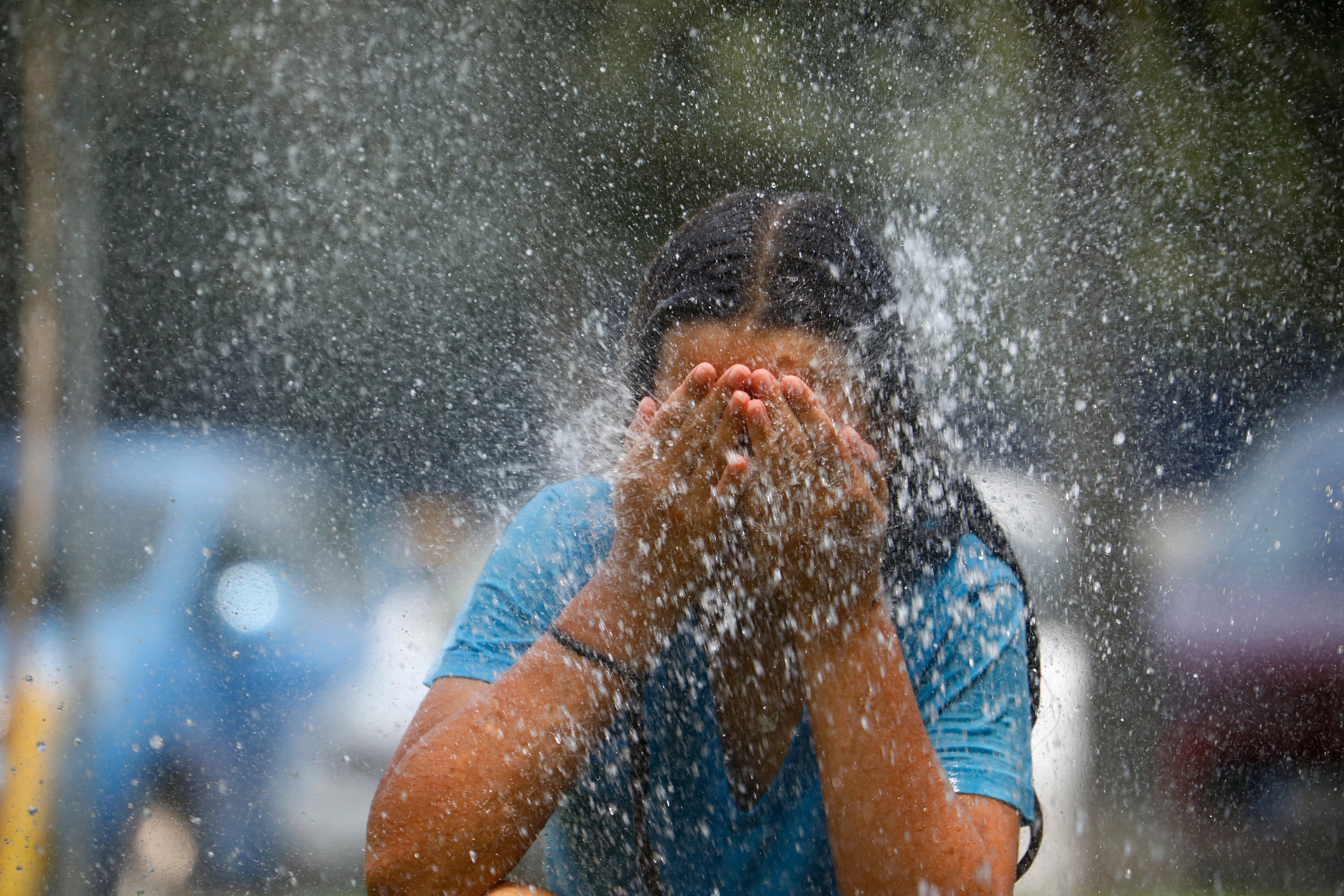 GRAFAND3270. CÓRDOBA, 28/06/2023.-Una joven se refresca en una fuente de una calle de Córdoba. La primera ola de calor que afecta a España este verano llega a su fin este miércoles con valores aún muy altos, hasta 42 grados, sobre todo en el centro y sur peninsular, aunque ya sin superar los umbrales establecidos para estos episodios de calor extremo. EFE/Salas
