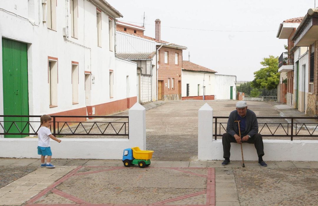 Un pequeño juega junto a una persona mayor en la localidad vallisoletana de Mayorga